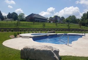 Grand Home Overlooking Large In Ground Pool With Tanning Ledge and Boulders