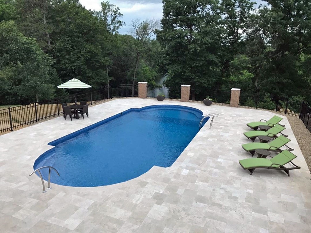 A Simple Tasteful Swimming Pool With Pale Granite Pavers and Metal Fencing