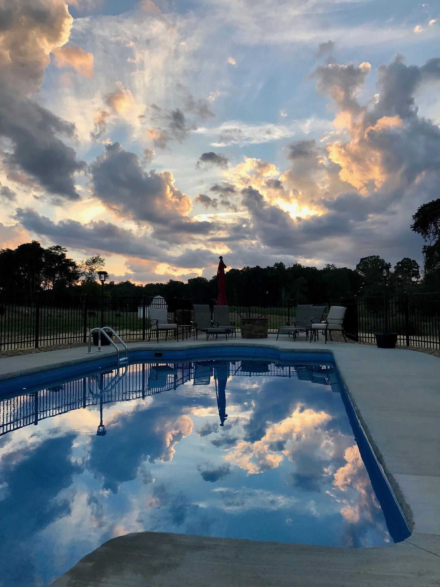 Absolutely Astounding Photo of Dark Swimming Pool at Sunset with Clouds and Sunbeams