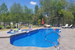 Fiberglass swimming pool with tanning ledge including submerged lounge chairs