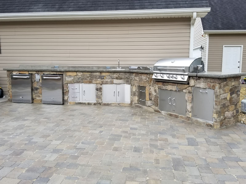 Outdoor kitchen with stainless steel appliances and rock face cabinets and marble counter