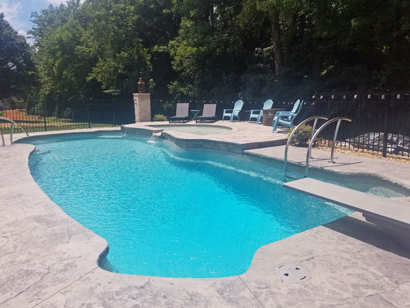 Deep fiberglass pool with diving board, tanning ledge and tasteful metal safety fence
