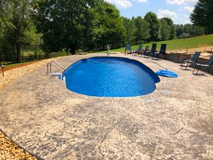 Large fiberglass pool on a big sloping lot with mature trees out in the countryside