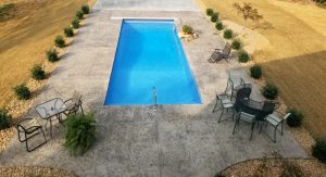 Large deep fiberglass pool with automatic cover system and slab + plumbing prepared for a pool cabana