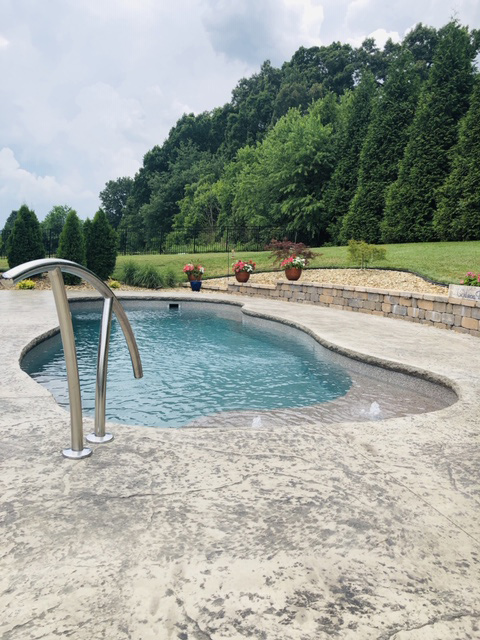 By the forests edge rests a fiberglass lagoon style pool with neat landscaping in Chuckey, TN