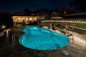 Bright blue pool water at night with cool landscape lighting in Johnson City, TN
