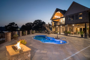 Night time shot of illuminated pool with fire features overlooking the lake at dusk in Morristown, TN