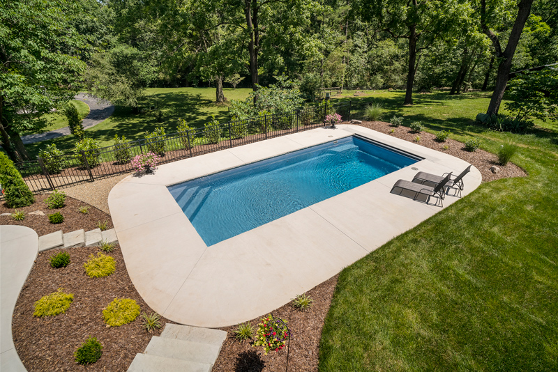 Overhead view of rectangular fiberglass pool with deep end set amids beautiful neat landscaping