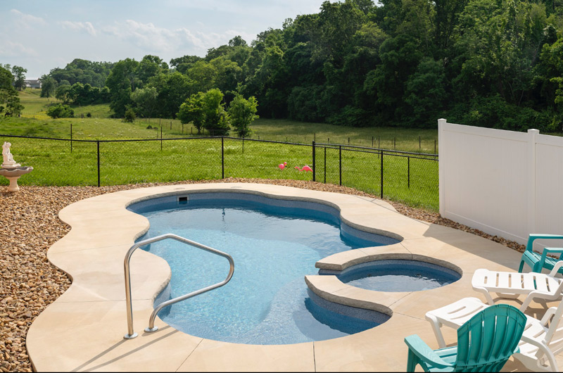 This petite Fiberglass Inground Pool was installed near Kingsport, TN, with a basic concrete and stone surround