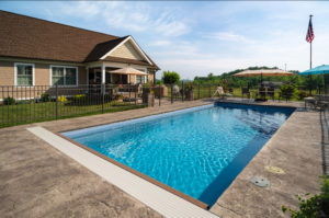 Good sized rectangular pool with large concrete decking area with many seating options and retractable cover system for safety
