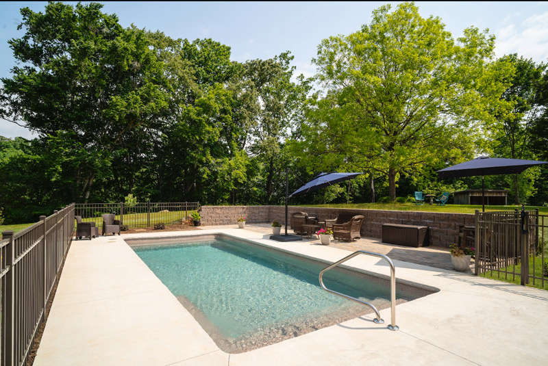 Rectangular pool near Kingsport TN with retaining wall creating a poolside nook for socializing and storing pool toys