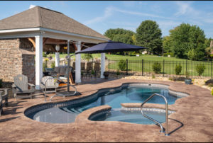 Huge pool cabana outdoor living area next to a lagoon pool and hot tub combo