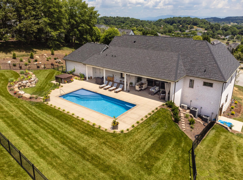 Aerial photography of a perfectly manicured back yard with swimming pool and dry stack boulder wall