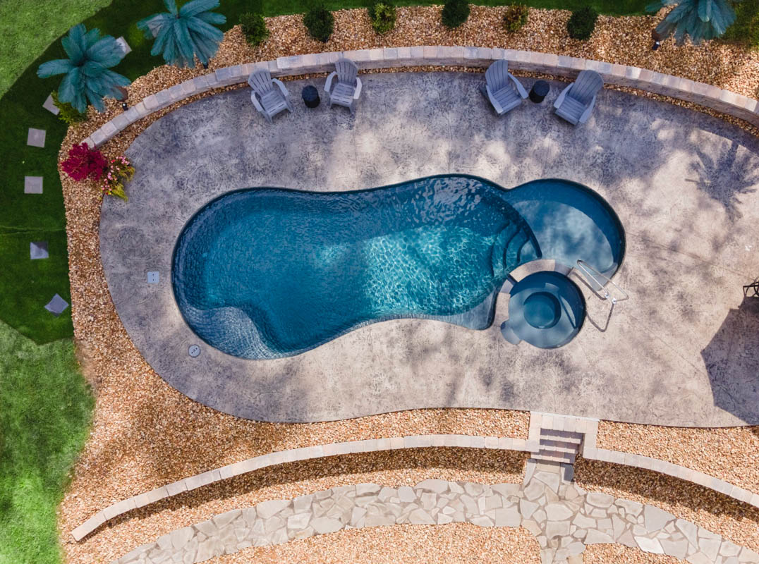 Dramatic overhead drone photo of swimming pool installation with lagoon shape and jetted soaker tub