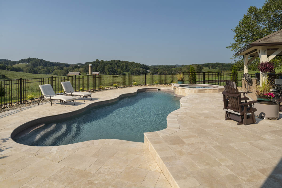 View of rolling farmland of East Tennessee in the background of an exquisitely hardscaped backyard pool area
