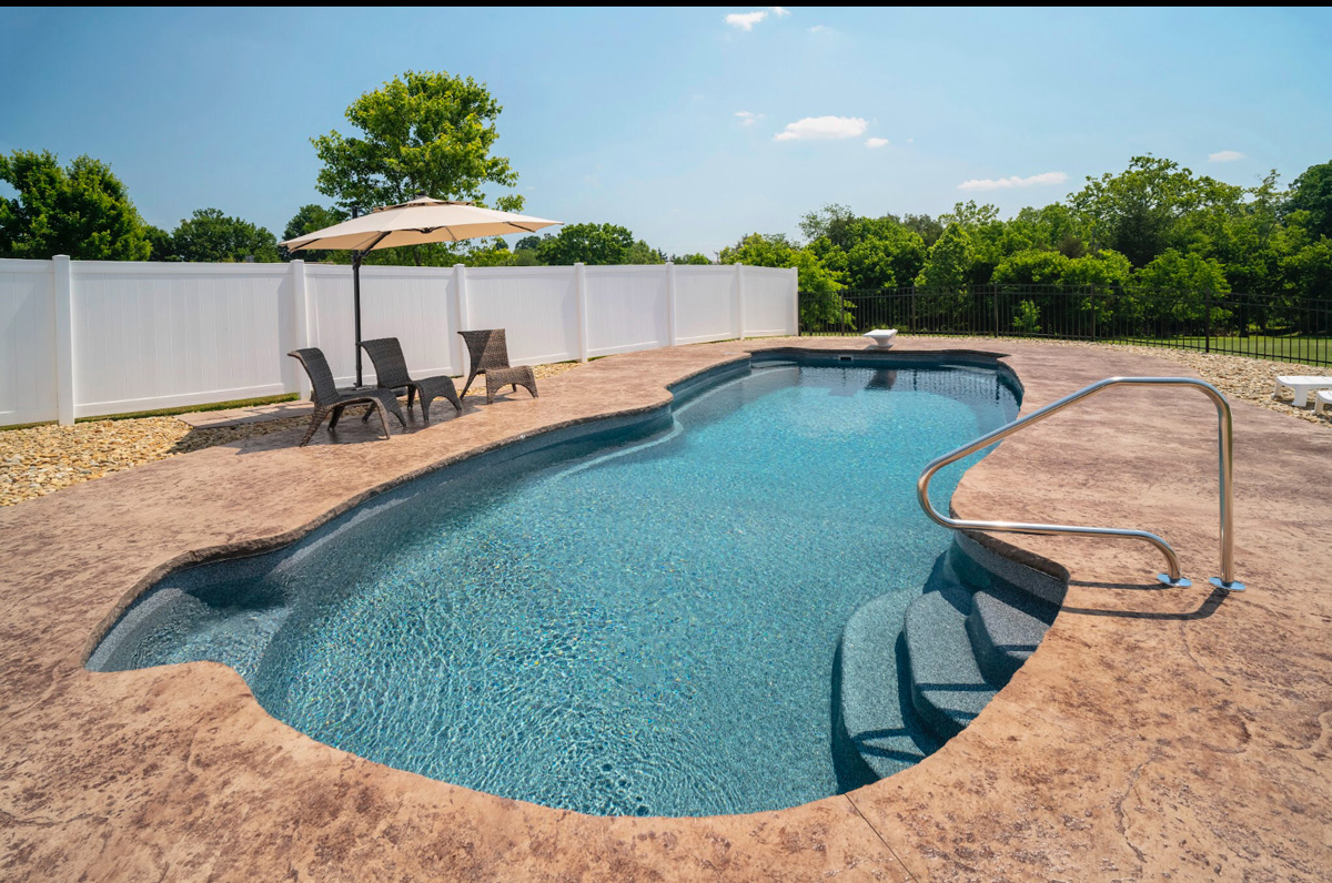 Large inground fiberglass pool with a deep end and diving board, as well as integrated seating and stairs