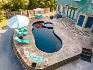 Simple small lagoon shaped pool with soaker tub creatively placed in small backyard