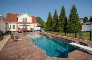 A fiberglass pool with deep end and diving board in a small backyard in Johnson City subdivision