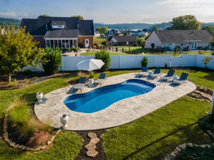 Delightful landscaping including decorative grasses and white privacy fence surround this backyard pool