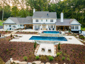 Expansive backyard pool area with two level pool and terraced concrete decking with various sitting areas