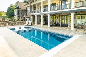 rectangular fiberglass pool with deep end set just beside house with patio and balcony