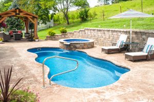 Steep sloped backyard in Jonesborough, Tennessee with retaining wall, hardscaping, and fiberglass inground lagoon pool