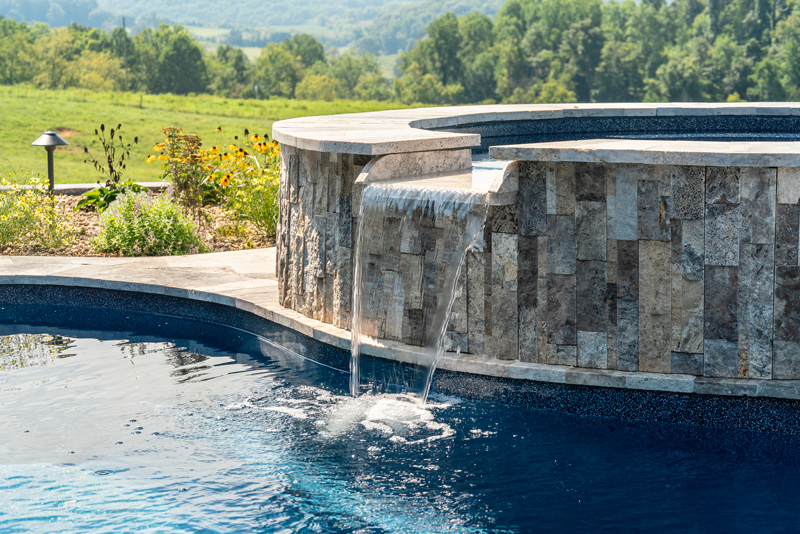 Detail of waterfall feature and hardscaping wrap on the poolside spa